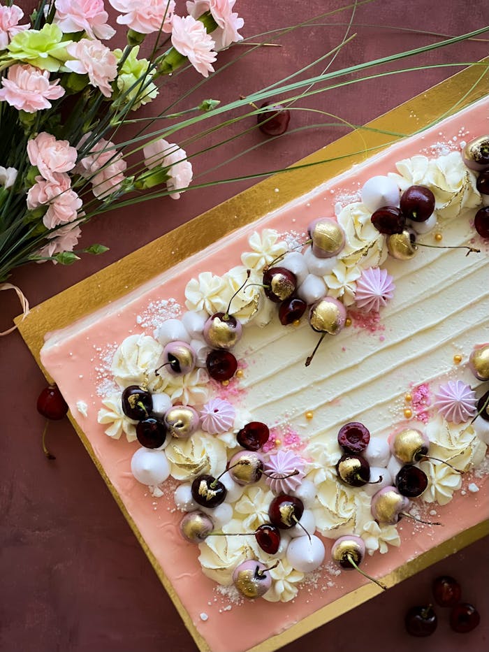 Beautifully decorated cake with cherries and gold accents, perfect for celebrations.