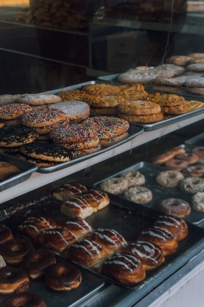 services-01 A delicious assortment of pastries and donuts showcased in a bakery window display.