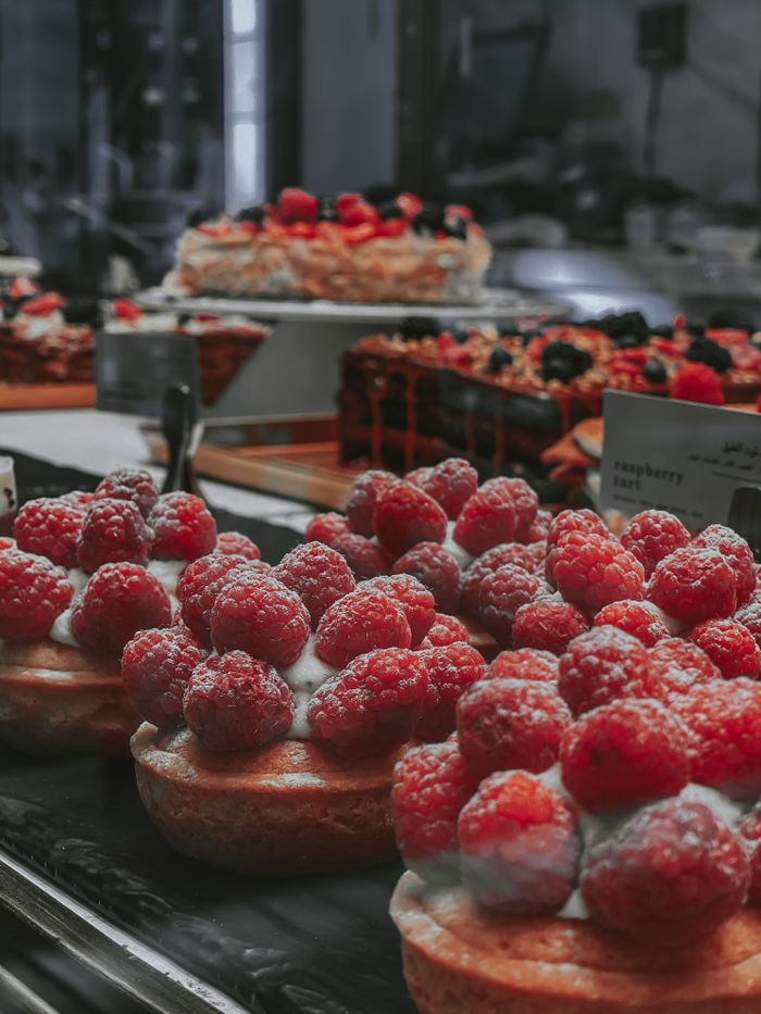 Close-up of raspberry tartlets in a bakery display showcasing luscious desserts.