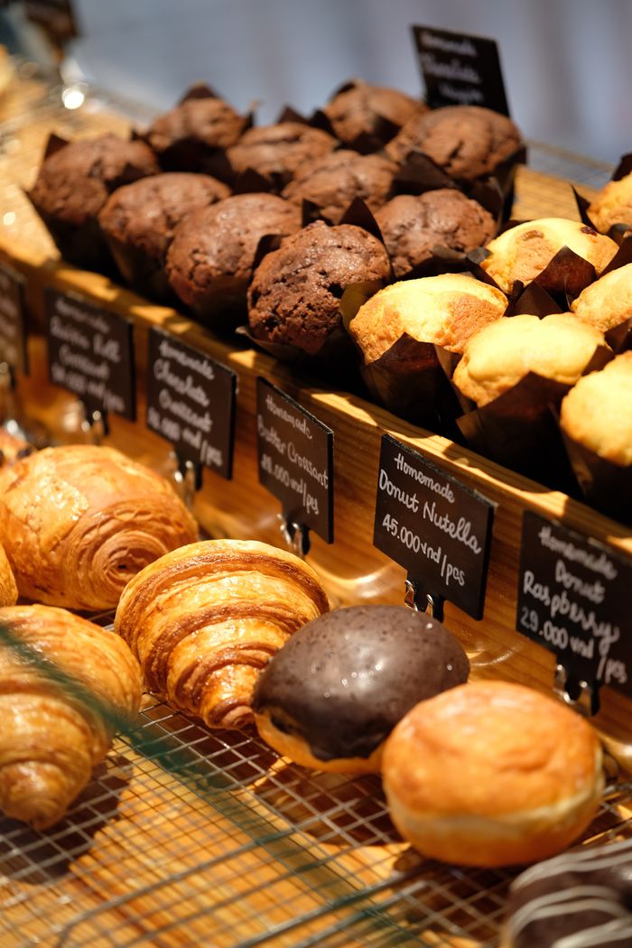 A tempting array of muffins and croissants displayed in a bakery. Perfect for breakfast lovers.