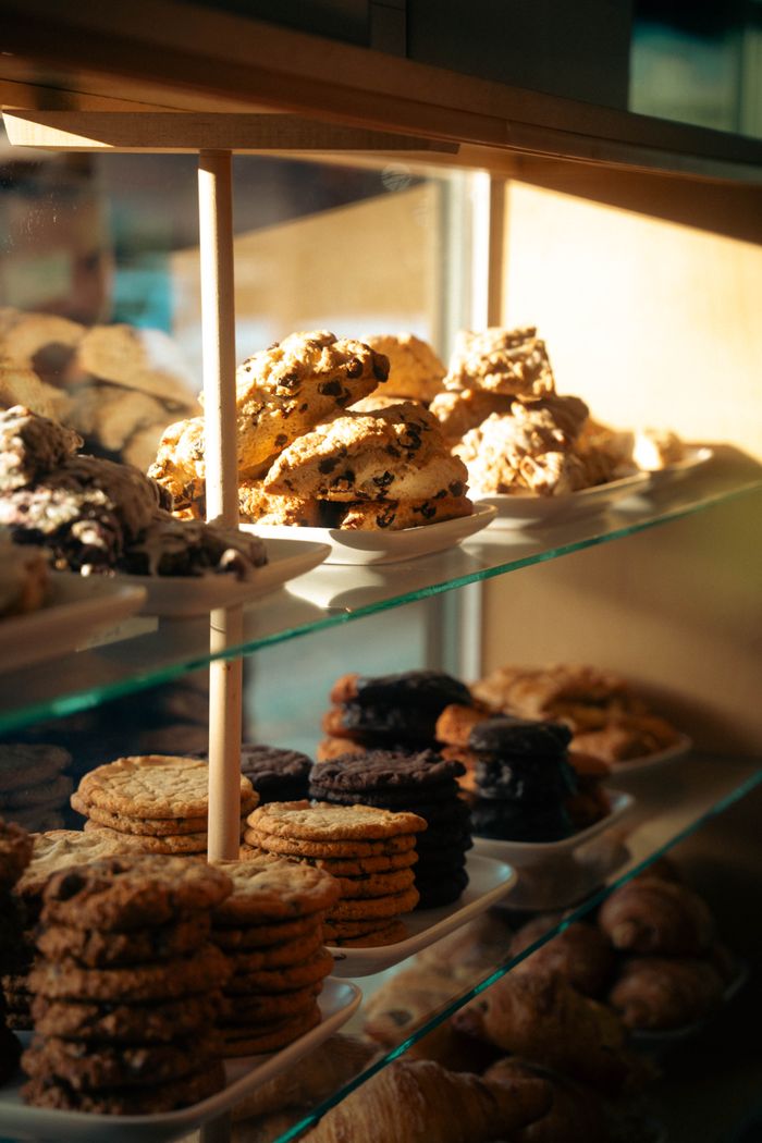 An inviting selection of cookies and pastries in a sunlit bakery display case.