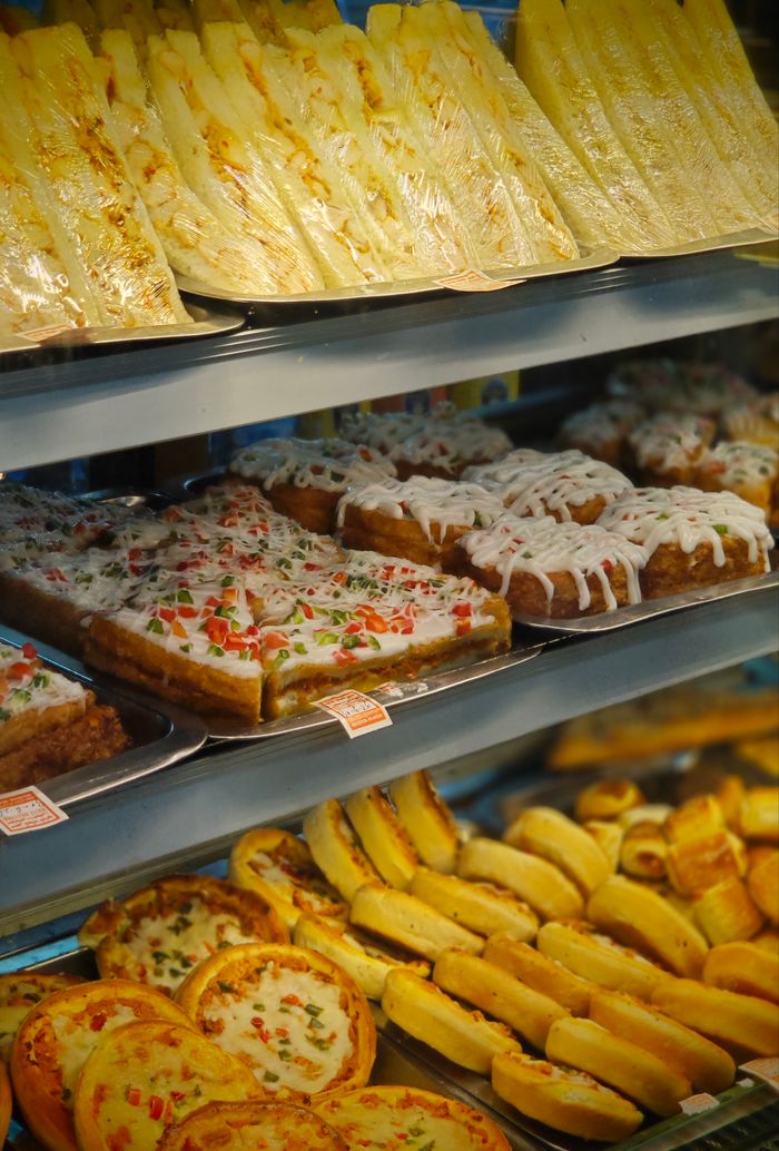 services-04 A tempting selection of pastries and pizza slices in a bakery display case.